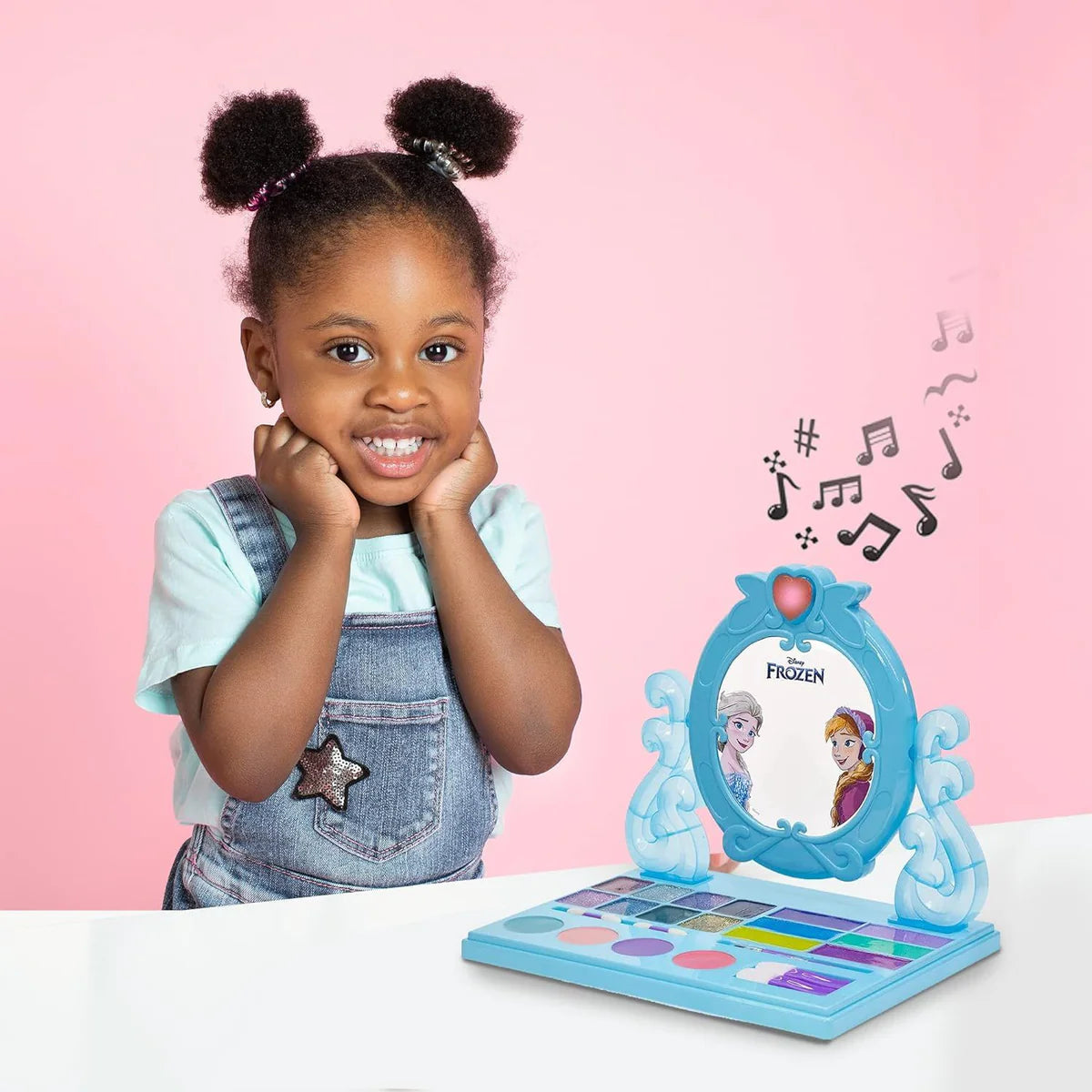 Child beside Disney Frozen cosmetic vanity set with mirror, makeup tray and music notes graphic
