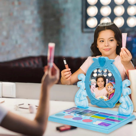 Girl using Disney Frozen cosmetic vanity mirror while holding makeup tubes beside the open tray