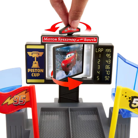 Close up of Disney Pixar Cars playset with fingers pressing red button above rotating screen