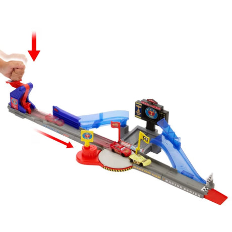 Disney Pixar Cars track playset with hand placing red car on launcher and black car on blue ramp