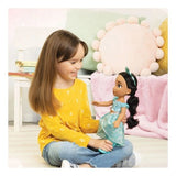 Child holding the Disney Princess My Friend Jasmine Doll while seated indoors
