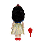 Rear view of the Disney Princess Snow White doll beside the red hairbrush 