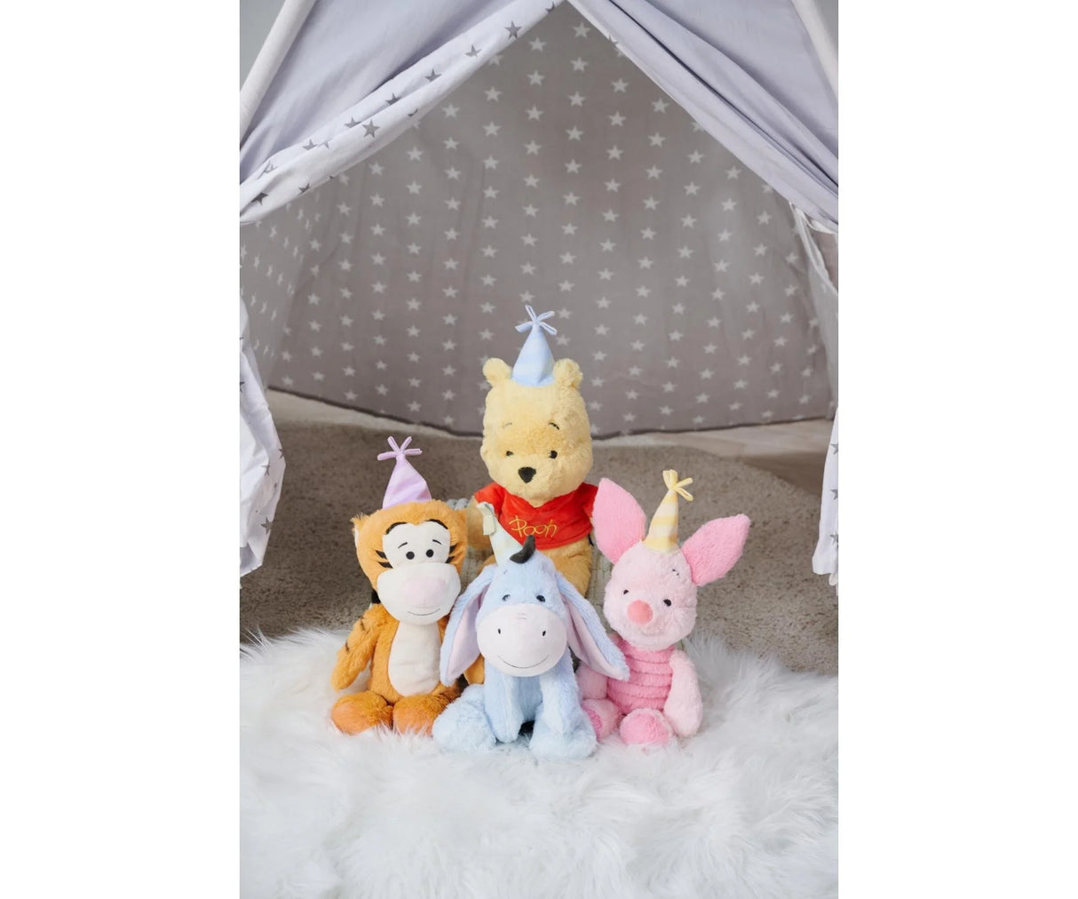 Disney Winnie the Pooh Anniversary 25cm plush displayed alongside Tigger, Eeyore and Piglet anniversary plush toys, all wearing party hats, inside a star-print play tent