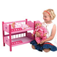 Child holding a doll beside the pink Dolls World bunk beds with two smaller dolls lying on the top bunk