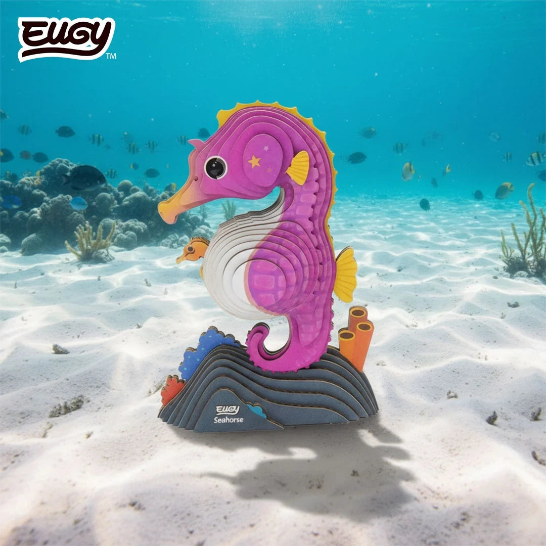 EUGY Seahorse 3D cardboard model with pink body, yellow fins and baby seahorse in its pouch, displayed on a sandy underwater seabed