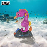 EUGY Seahorse 3D cardboard model with pink body, yellow fins and baby seahorse in its pouch, displayed on a sandy underwater seabed