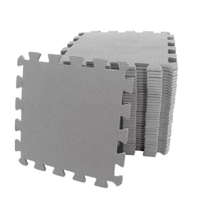 Stack of grey interlocking EVA foam play mats with one tile leaning forward showing textured surface and puzzle edge design
