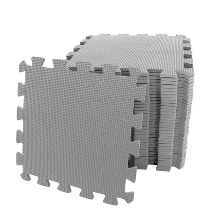 Stack of grey interlocking EVA foam play mats with one tile leaning forward showing textured surface and puzzle edge design