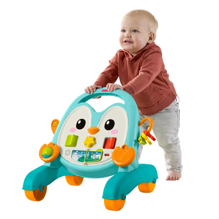 Baby standing and pushing the Fisher-Price Musical Penguin Activity Walker using the turquoise handle