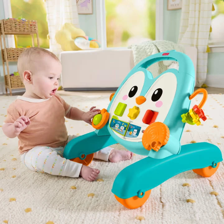 Baby seated beside the Fisher-Price Musical Penguin Activity Walker reaching for the activity controls