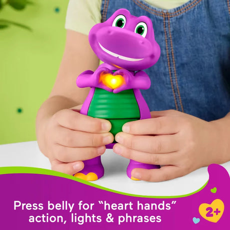 Child pressing Fisher-Price Barney's World Heart Hands Barney with his hands raised around the glowing heart on his chest
