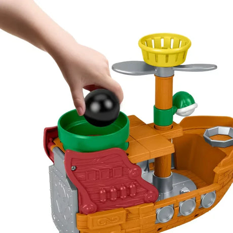 Close up of hand placing black cannonball into the green basket on Bowser’s Airship playset