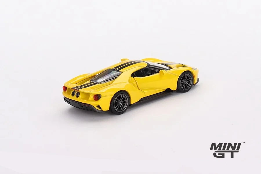 Mini GT Ford GT Triple Yellow LHD model viewed from the rear left showing the twin round tail lights, rear grille, black centre stripes and dark wheels
