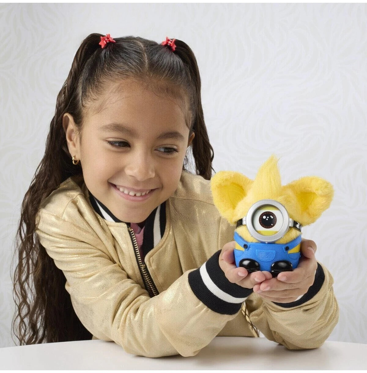 Child holding Furby Furblets Minions plush toy with goggle accessory