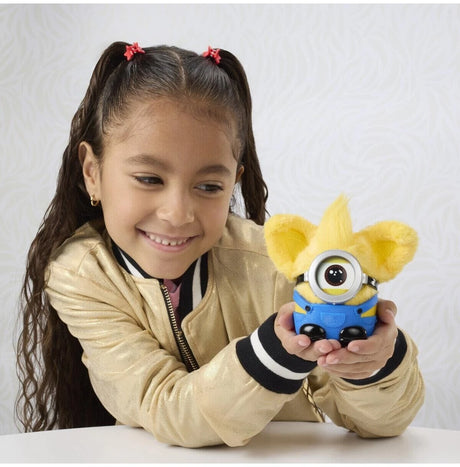 Child holding Furby Furblets Minions plush toy with goggle accessory