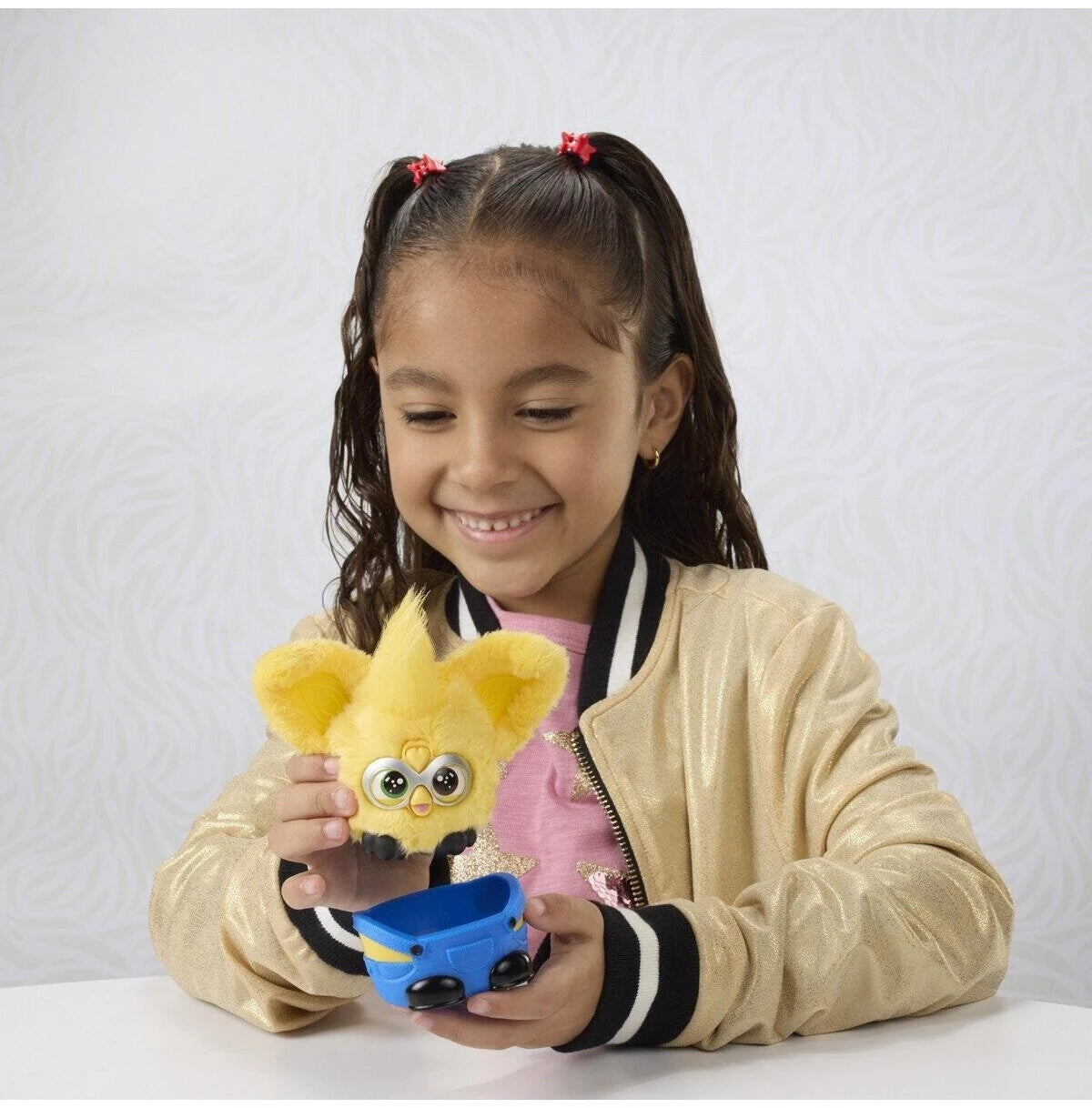 Child playing with Furby Furblets Minions plush toy at a table