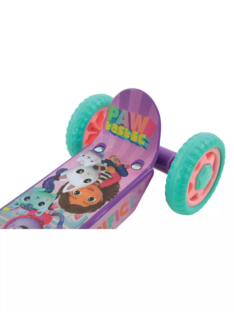 Low-angle view of the scooter footdeck showing Pawtastic text, Gabby's Dollhouse character artwork and two teal rear wheels with pink hubs