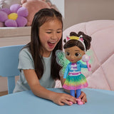 Child with the Gabby's Dollhouse Dandelion Magic Gabby Doll standing on a table with fairy wings glowing green
