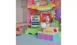Hand sliding the grey baking tray into the open oven beside Cakey Cat on the rolling pin and the blue chef cat figure by the pink egg box