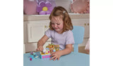 Child playing with Cakey Cat's Fairy Kitchen on a blue table, with the kitchen counter, oven, illustrated backdrop and figures arranged in front