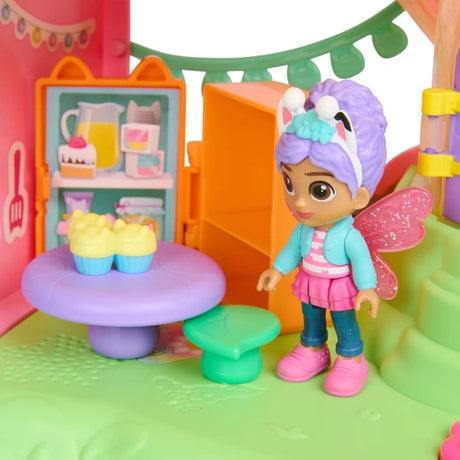 Gabby figure with pink wings beside a purple table with two cupcakes and a green stool