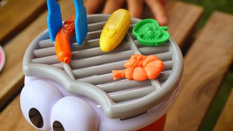 Close-up of BBQ Party toy grill with plastic food and tongs in action – Ireland