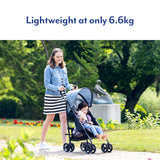 Woman pushing a child in a Graco EZLite Midnight stroller in a garden park