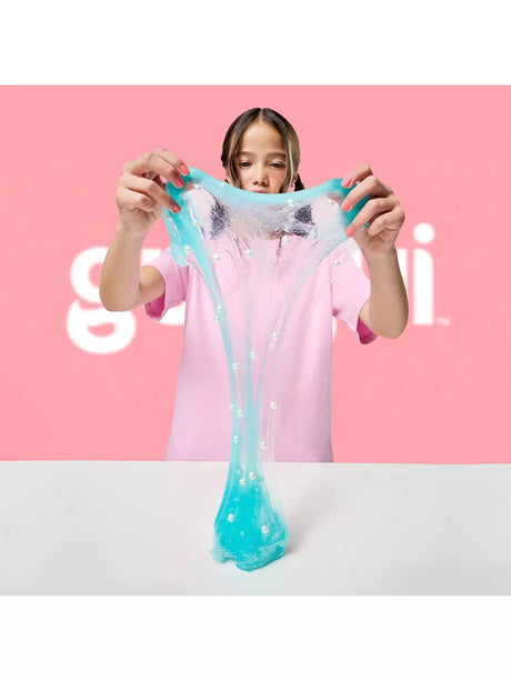 Gui Gui Deluxe Twin Pack teal clear shimmer slime stretched wide with white pearl beads embedded throughout, pulled upward from a white surface