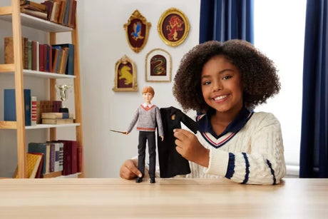 Child removing the Gryffindor robe from the Harry Potter Ron Weasley fashion doll
