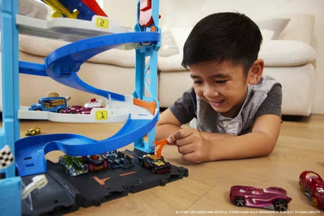 Child playing with Hot Wheels City Transforming Race Tower Playset, racing cars down spiral tracks in Ireland.