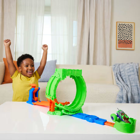 Hot Wheels Monster Trucks Mutant Chaos Loop Challenge assembled on a table with a smiling child raising both arms behind it.