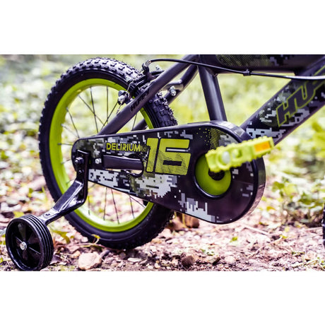 Close up of Huffy Delirium bike chain guard, rear wheel, black stabiliser wheel and green pedal