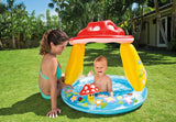 Child sitting in the Intex Mushroom Baby Pool beside an adult on grass outdoors