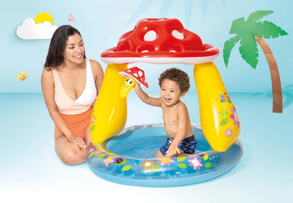 Child sitting in the Intex Mushroom Baby Pool beside an adult in a studio scene