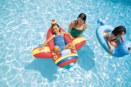 Red plane and blue seal Intex Pool Cruisers floats in a swimming pool with children and an adult