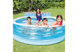 Four children sitting in the Intex Swim Center Family Lounge Pool on grass