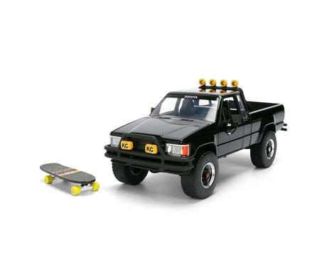 Jada Toys Back to the Future black 1985 Toyota SR5 Pickup diecast model displayed with Marty's skateboard on a white background.