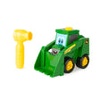 Green John Deere Build A Buddy skid steer toy with front bucket and yellow wheels beside a yellow ratchet tool on white background