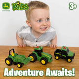 Child leaning over wooden table with three John Deere mini vehicles, John Deere KIDS logo, “3+” age mark and “Adventure Awaits!” text