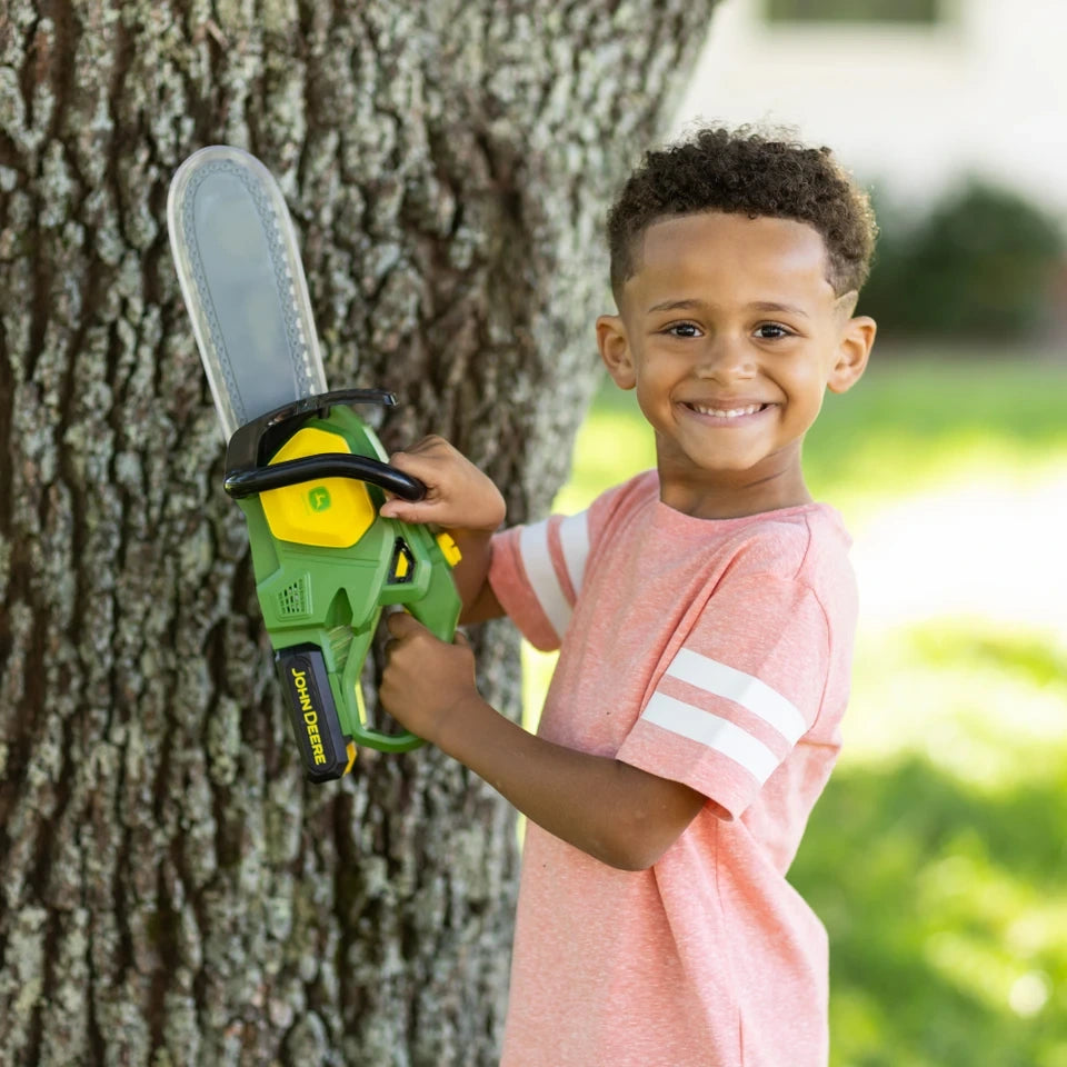 John Deere Motorised Chainsaw held by smiling child beside tree trunk