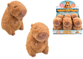 Two cuddly capybara plush toys beside a cardboard display box filled with capybara soft toys