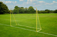 Yellow metal football goal with white netting beside a white pitch line on grass