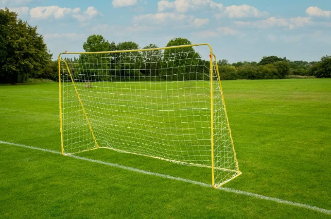 Yellow metal football goal with white netting beside a white pitch line on grass