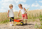 Two children with a red and yellow kids metal wheelbarrow