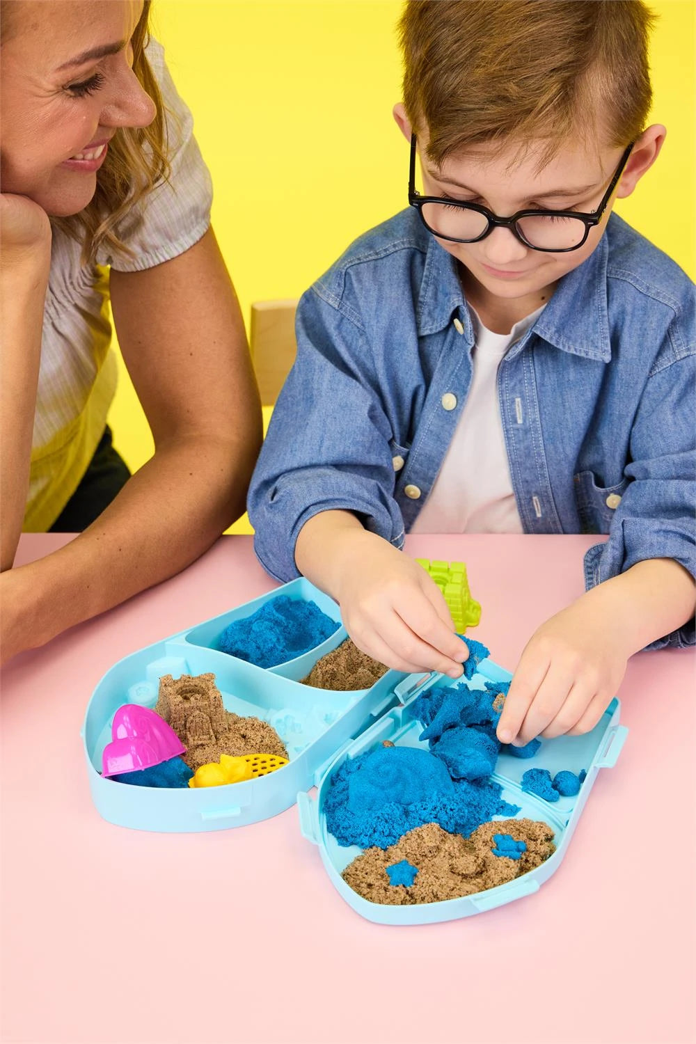 Child shaping blue and brown Kinetic Sand inside the open Surf N' Sand Paradise case