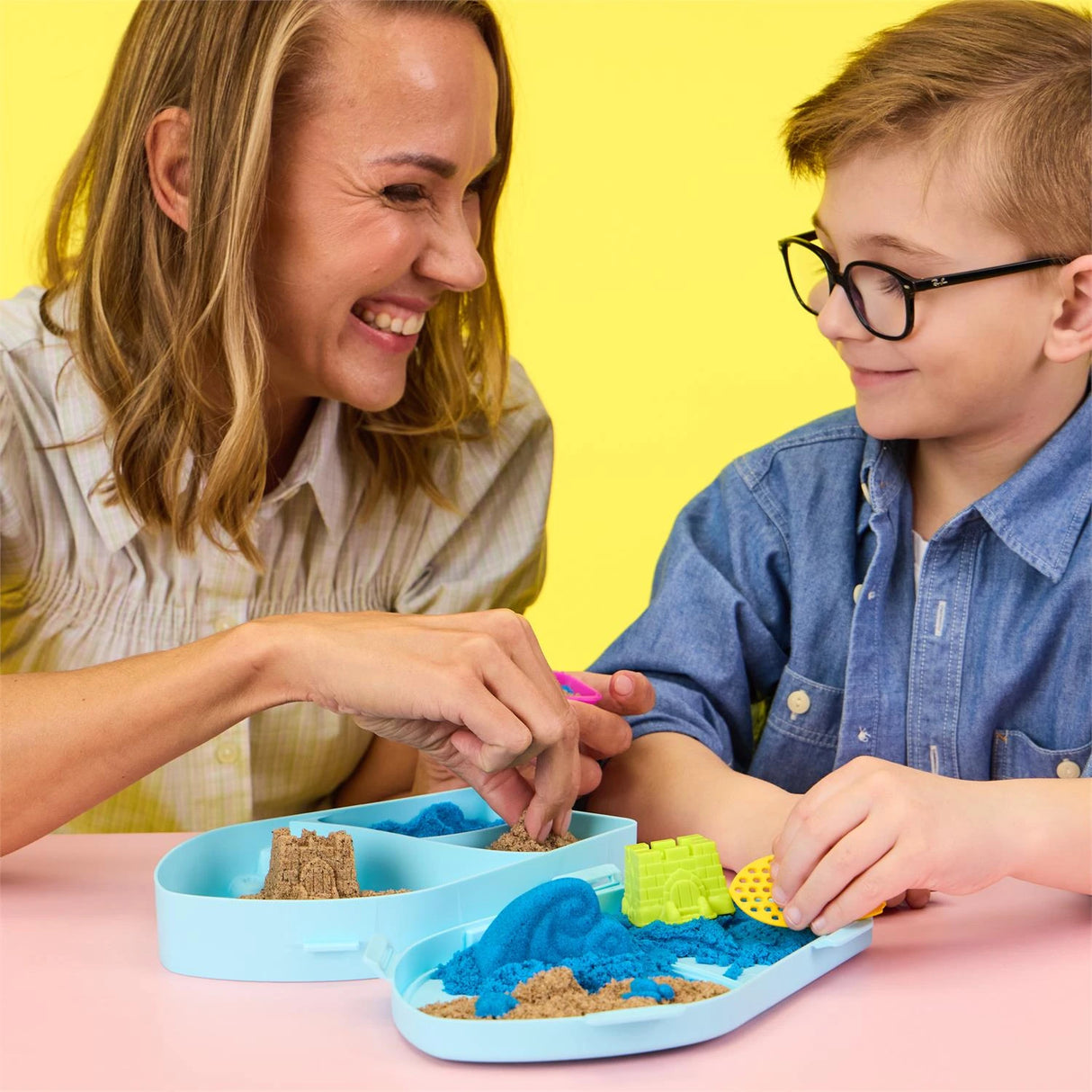 Child using the Kinetic Sand Surf N' Sand Paradise set with an adult beside him