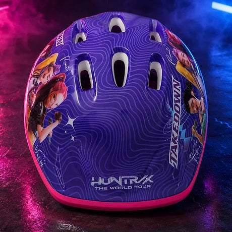 Front view of KPop Demon Hunters Takedown Helmet showing HUNTR/X The World Tour branding, purple patterned shell and ventilation openings against pink and blue neon lighting