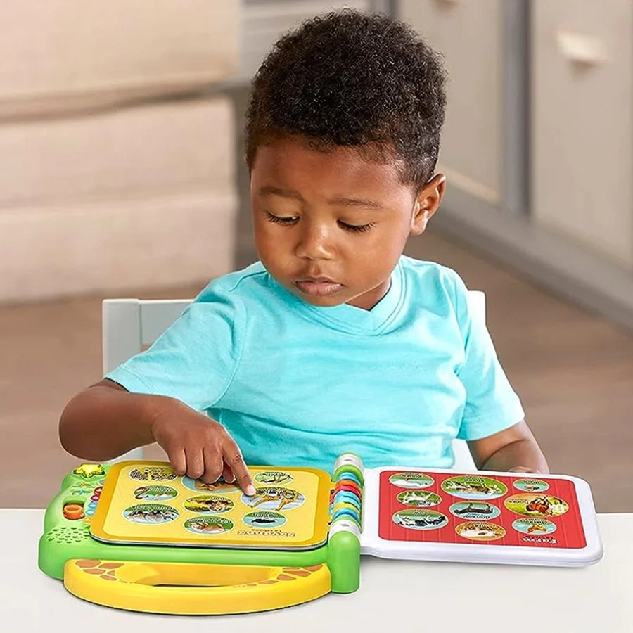 Young boy wearing a turquoise shirt pointing at animal pictures in an open LeapFrog 100 Animals Book on a table