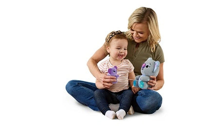 Adult and toddler sitting on floor holding LeapFrog Cuddle & Learn Koalas plush toys