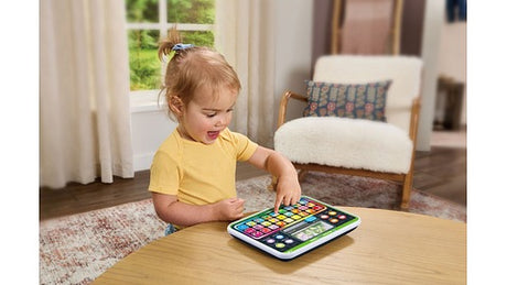 Toddler using the LeapFrog My First ABC Tablet on a wooden table in a living room